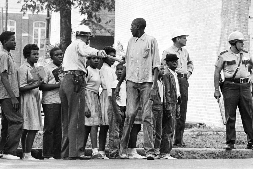 African American children participating in a Civil Rights protests wait for a police van to take them to jail in Birmingham, Alabama.
