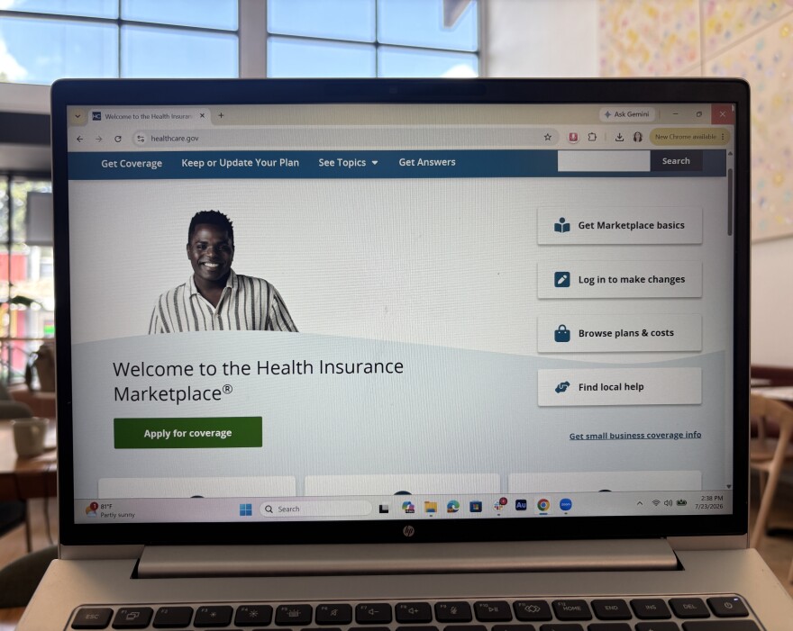 A laptop screen is open to healthcare.gov which has a button to apply for coverage.