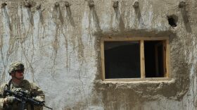An US contractor working with the 10th Mountain Division US Army keeps an eye on the surroundings standing against a wall at the provincial head Intelligence Office of the Afghan National Police in Ghazni city.