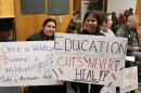 A mother and daughter hold signs at a Corvallis School Board meeting