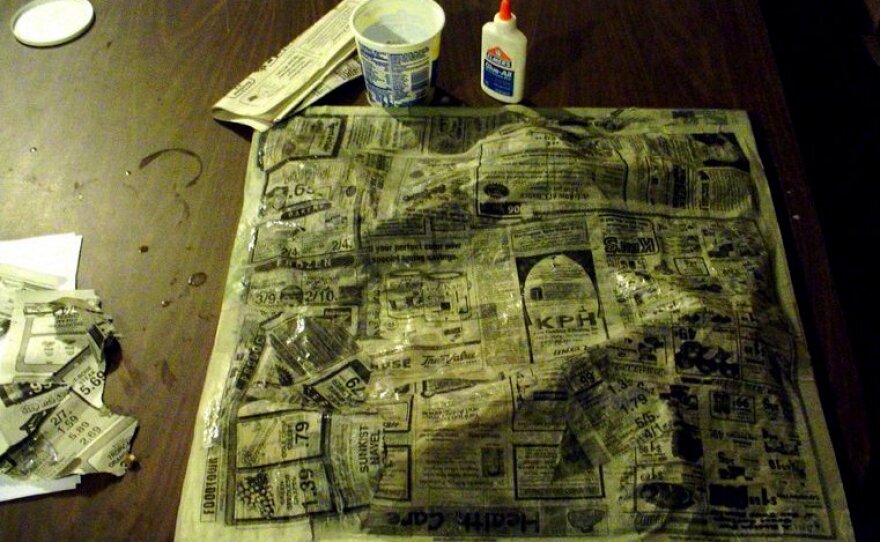 The entire board and brown paper bags were covered with newspaper covered in a mixture of water and glue. 