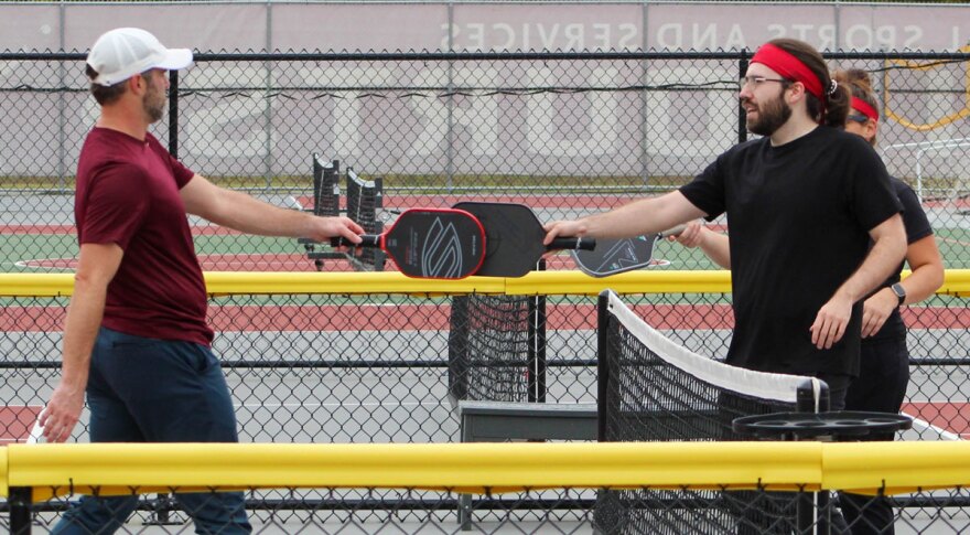 Pickleball players tap paddles across the net.