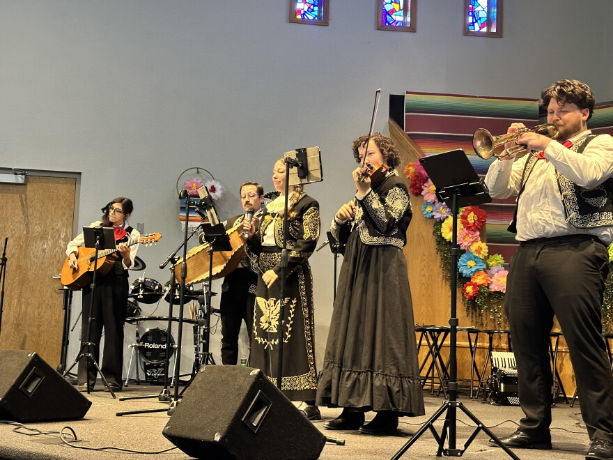 A mariachi band dressed in ornate black and white plays various instruments