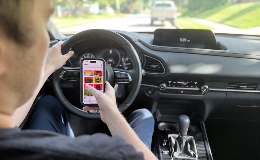A person holding their phone while driving.