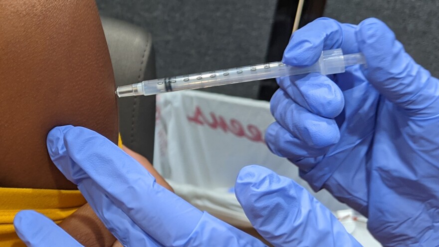 A pharmacist administers a COVID-19 vaccine 