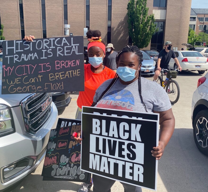 Photo of woman in holding a Black Lives Matter sign.