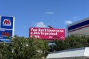 A bright pink billboard with white writing that says "You don't have to be a Jew to protect Jews."