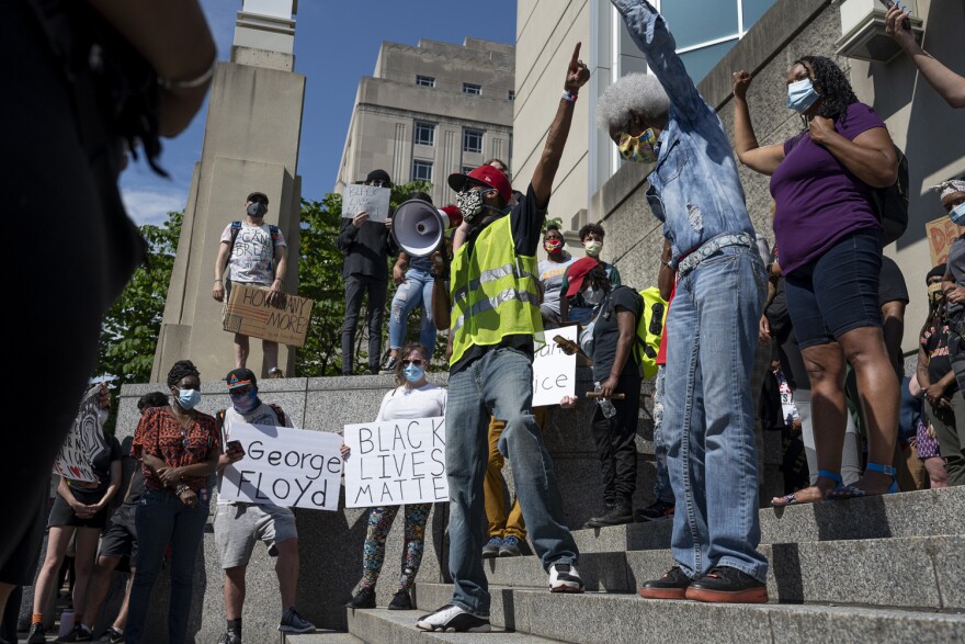 Protesters listened to speakers on the steps of the City Justice Center on Monday.