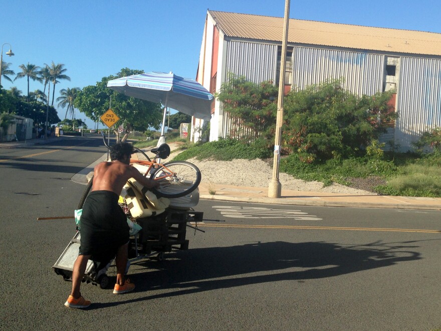 A homeless man who had been living in a large encampment in the Kakaako neighborhood of Honolulu pushes his belongings away as city officials sweep the area on Oct. 8. Honolulu city crews cleared the final section of one of the largest homeless encampments in the nation, once home to hundreds of people.