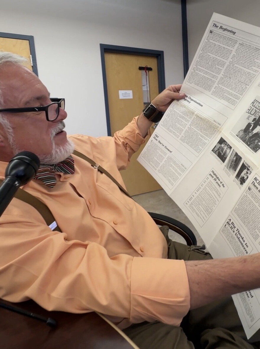 Bruce Darling, president of the Center for Disability Rights, looks through a 1986 publication by the local disability rights organization that was named at the time, Rochester Center for Independent Living. James Leary, who participated in the 1966 picket, is photographed in this issue.