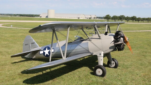small gray plane sits in grassy field