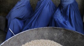 Burqa-clad Afghan women wait to buy chickpeas from a shop in Kabul earlier this year.