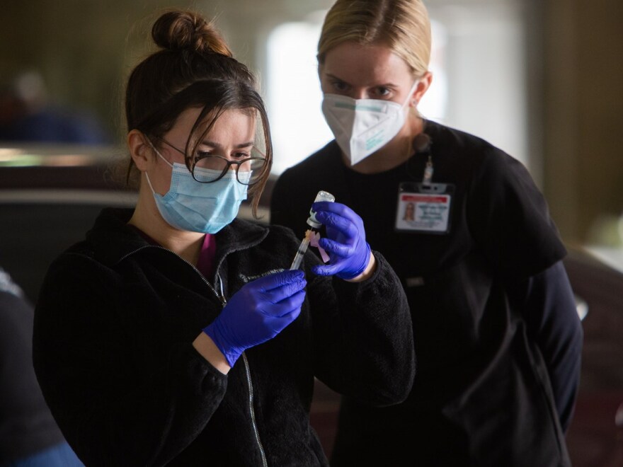 California Army National Guard Medic Jenny Rafailov prepares syringes with the Moderna COVID-19 vaccine on Thursday, Jan, 21, 2021 while nurse Katherine Ambrose watches.