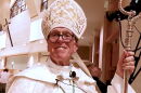 older man catholic bishop clothing holding staff and wearing a miter