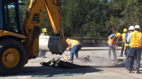 DOT workers repairing bridge approach damaged by October floods.