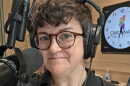 A person wearing headphones standing behind a microphone