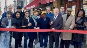 Lark Street Business Improvement District leaders are joined by local lawmakers and business owners to cut a ribbon during a celebration of new businesses on the strip on Wednesday, April 8, 2026.