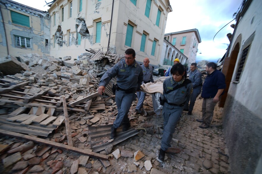 Rescuers carry a victim among damaged buildings after a strong earthquake hit Amatrice, Italy, on Wednesday.