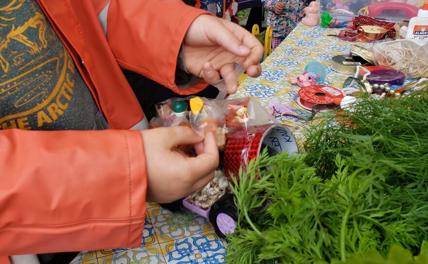 Luce Raderman applies tape to his zucchini car for Zucchini Fest at the Homer Farmers Market on Saturday, Aug. 26 in Homer.