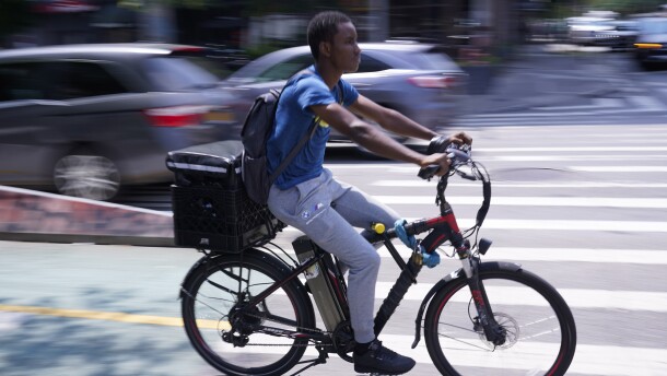 A delivery worker rides a motorized bicycle in New York, Tuesday, July 25, 2023.