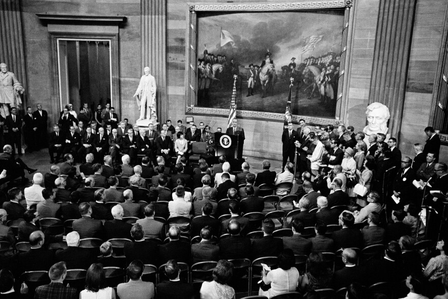 Black and white photo of President Lyndon Johnson at a podium speaking in the rotunda of the Capitol in Washington