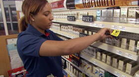 This undated photo provided by CVS Health, a CVS store employee removes tobacco products from the store shelves.