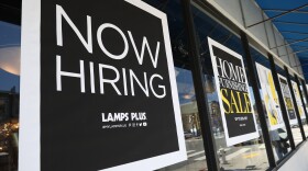 A pedestrian walks by a "Now Hiring" sign outside of a Lamps Plus store in San Francisco on on June 3. Four states, including Mississippi, are moving to end an extra $300-a-week unemployment benefit, arguing the pay is discouraging people from finding work.