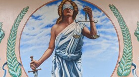 A mural of a blindfolded woman with a sword in one hand and a set of scales in the other.