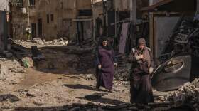 Palestinian women walk past an area damaged after an Israeli military raid in Jenin refugee camp in the West Bank. (Majdi Mohammed/AP)