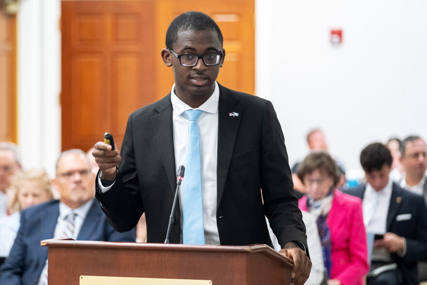 A student with a blue tie stands in front of a podium.