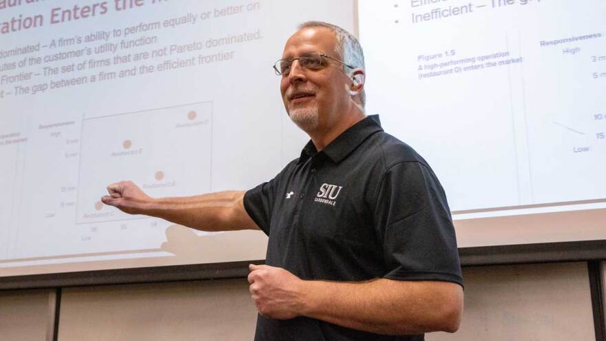 Professor delivers lecture in front of projection screen