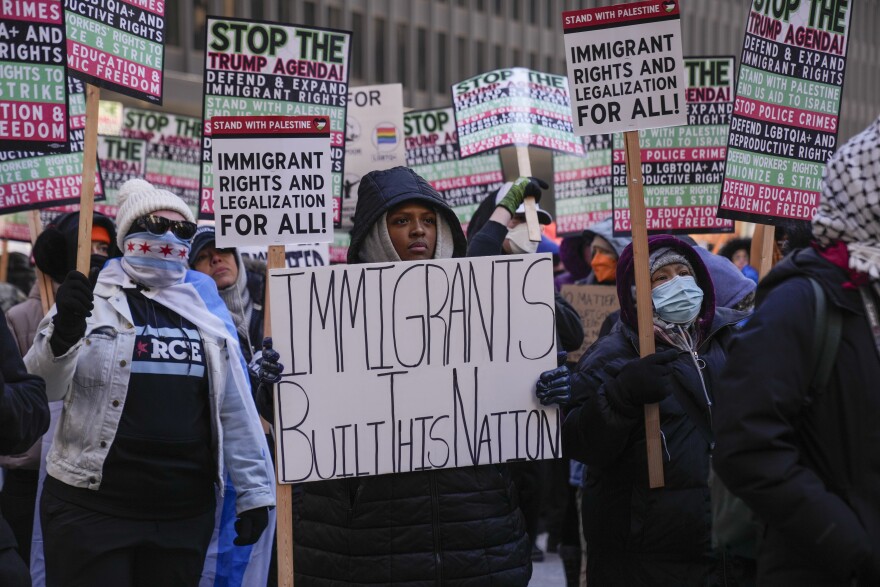 Protesters carry signs, including a person holding a sign that says "immigrants built this nation"