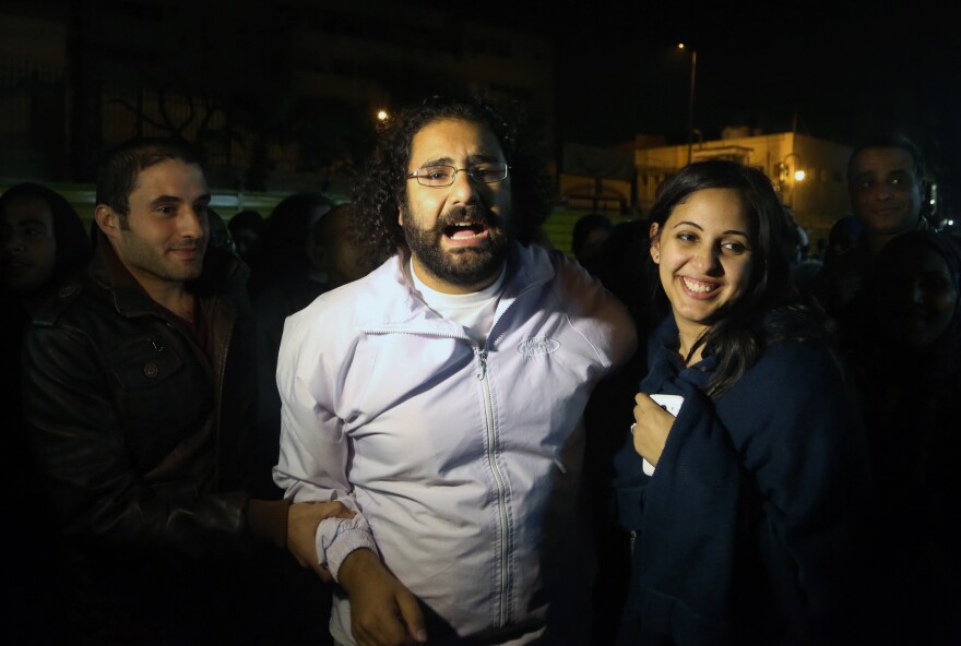 Alaa Abdel Fattah (center), a prominent activist and a leading figure in the 2011 uprising against Egyptian autocrat Hosni Mubarak, is welcomed by his wife after he was released from the main central security office in Cairo on Sunday.