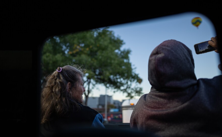 From left, balloon crew chief Penny Madanick and Renee Marshall sit in the back of a chase crew pickup truck – taking pictures of the Dawn Patrol on Monday morning.