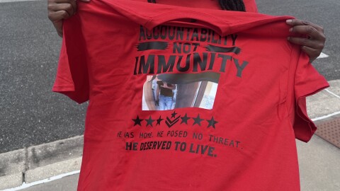 A supporter of the Fortson family holds up a t-shirt that reads "accountability not immunity."