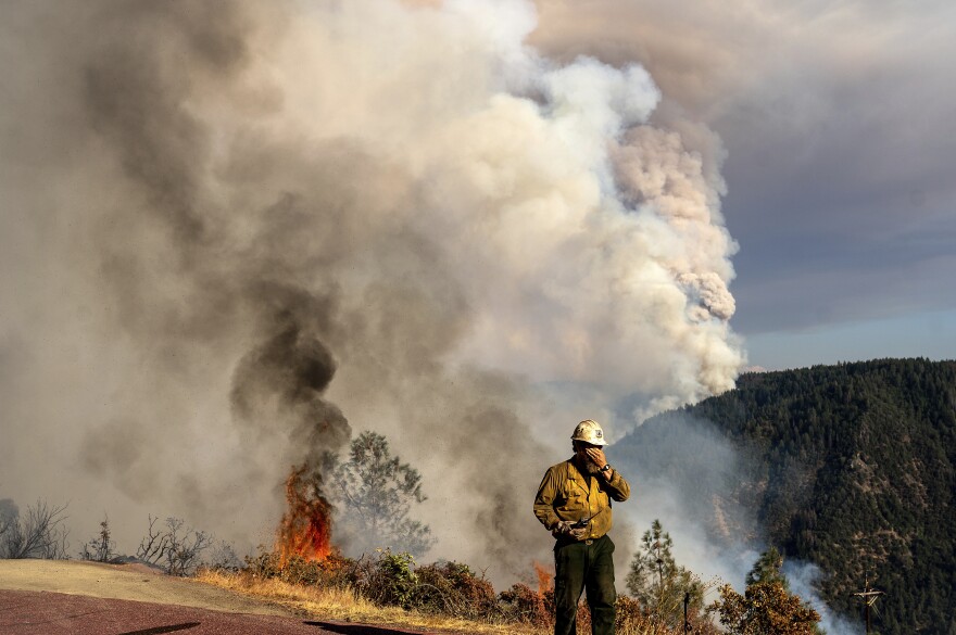 A firefighter rubs his face while battling the Mosquito Fire along Mosquito Ridge Road in Placer County, Calif., on Thursday.