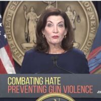 Gov. Kathy Hochul stands at a podium that says, "COMBATING HATE PREVENTING GUN VIOLENCE," in front of the state seal and between a U.S. and state flag.