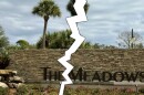 Large sign in front of community says THE MEADOWS, but in this illustration photo a lightning-looking tear zigzags vertically to give the appearance the image and sign have been cut in half 