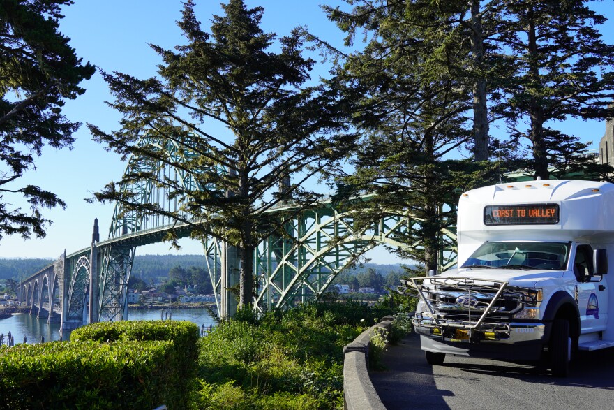 A bus parked within view of a bridge.