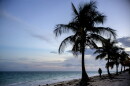 FILE - A woman walks along an ocean coast in Freeport, The Bahamas, Aug. 31, 2019. 