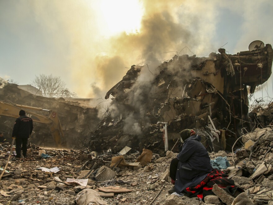 People stand by a collapsed building in Kahramanmaras, in southern Turkey, on Sunday.