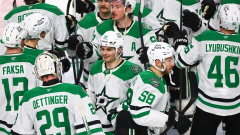 Hockey players in Dallas Stars uniforms gather on the ice.