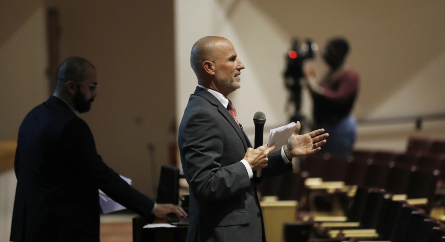 Addison Davis holding a microphone and addressing a crowd