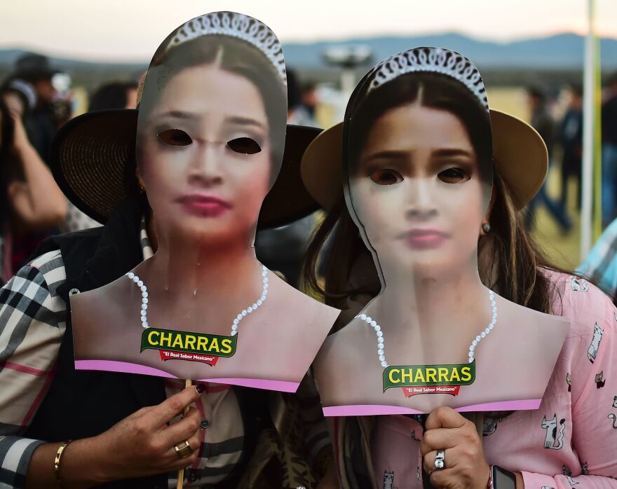 Two women hold masks depicting Mexican teenager Rubi Ibarra during her 15th birthday party on Monday.