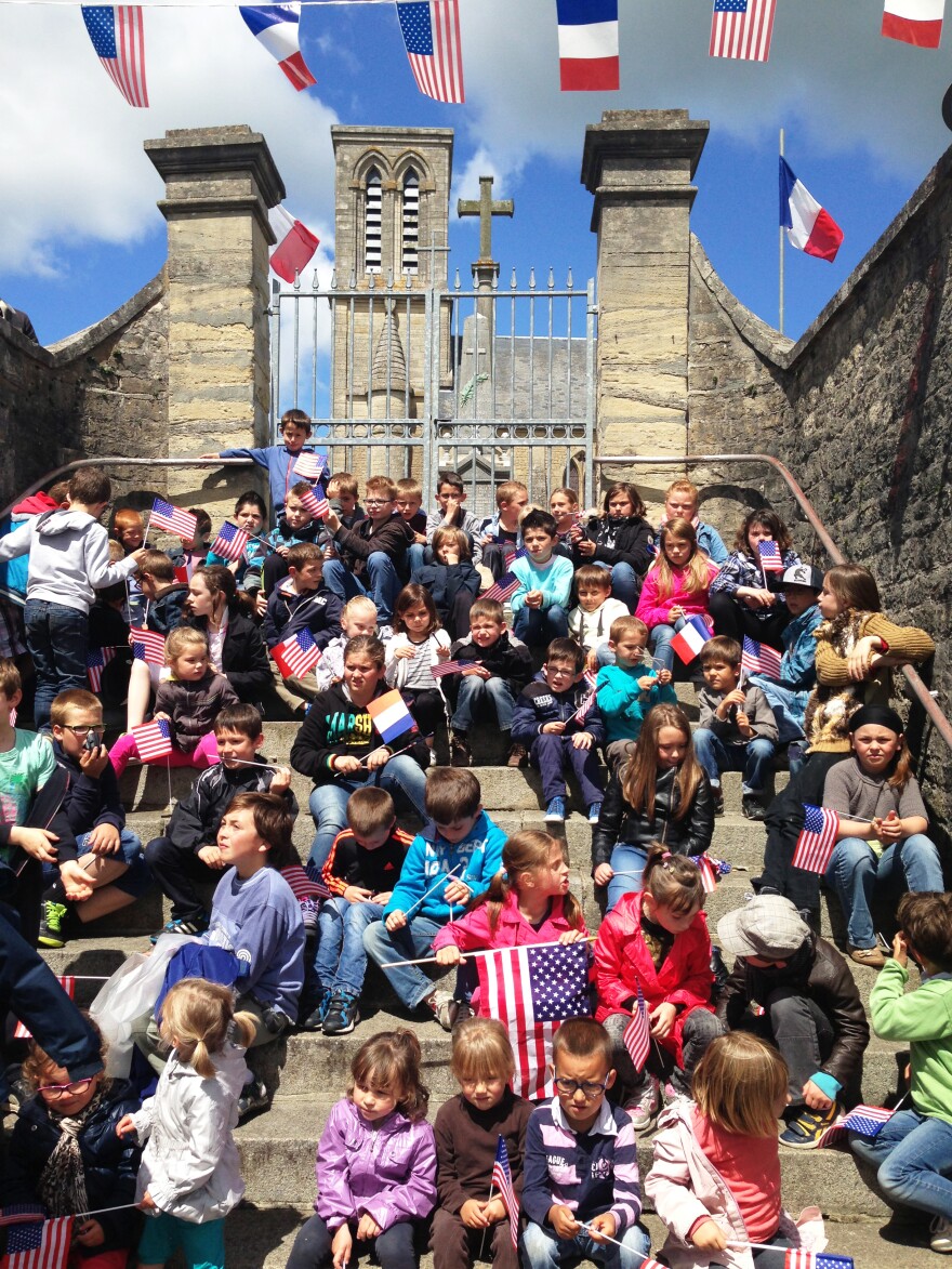 A group of children in La Cambe wave French and American flags at the unveiling of a plaque honoring the U.S. troops who liberated the village.