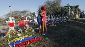 FILE - This Feb. 19, 2018 file photo shows Denyse Christian, hugging her son Adin Christian, 16, a student at the school, at a makeshift memorial outside the Marjory Stoneman Douglas High School, where 17 students and faculty were killed in a mass shooting in Parkland, Fla. Parkland city’s historian Jeff Schwartz is setting a plan in motion to collect, archive and preserve the Marjory Stoneman Douglas mementos. Meanwhile, school administrators have vowed to build a memorial after the demolition of the building where the Feb. 14 attack took place. (AP Photo/Gerald Herbert, File)