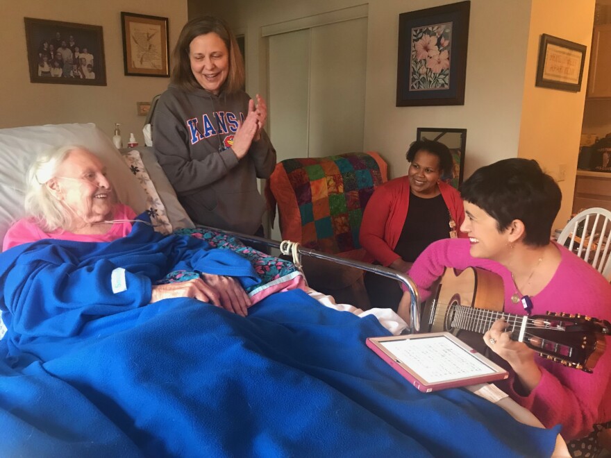 Hospice patient Dorothy Matejka enjoys a music therapy session with her daughter Nancy Daake, standing, and music therapists Alison Cole and Kathryn Coccia, seen here with her guitar.