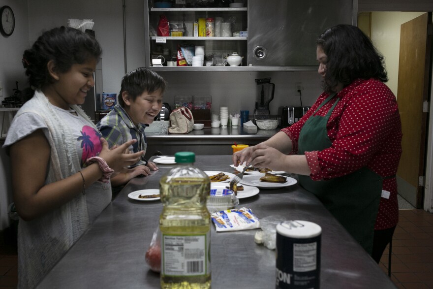 Rosa's children Maria and Juan Pablo joke around while Rosa puts fried plantains on their plates.