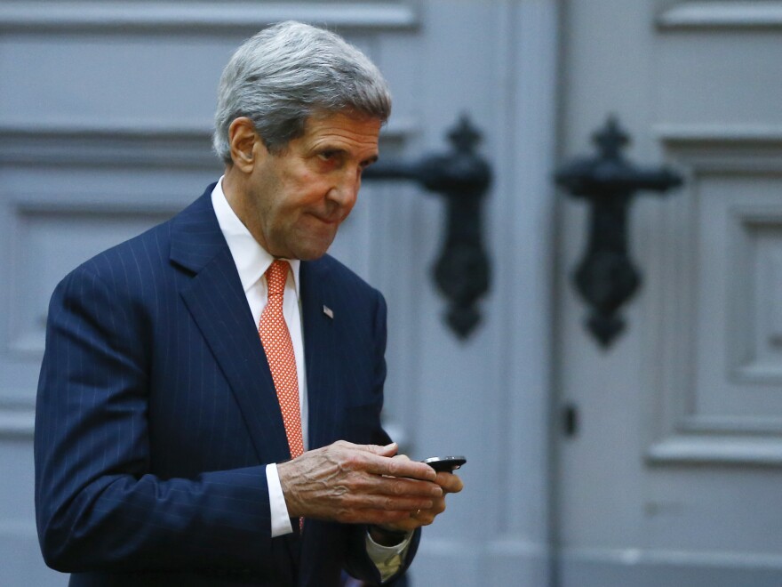 U.S. Secretary of State John Kerry looks at his phone as he leaves a meeting in Vienna on Friday.