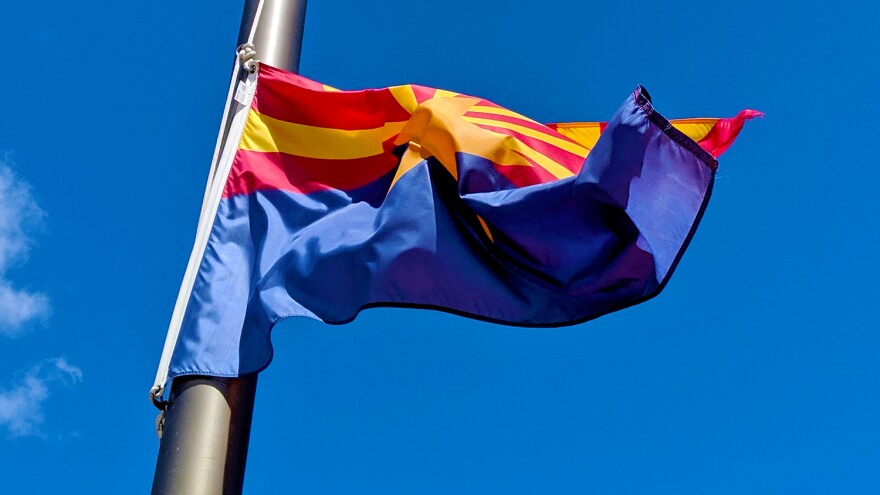 Flag with yellow star, red and yellow sun rays and blue bottom flapping in wind on blue sky background